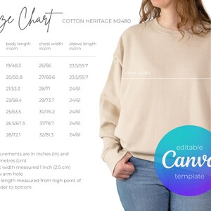 May include: A beige crewneck sweatshirt shown with a size chart for Cotton Heritage M2480. The chart lists body length, chest width, and sleeve length in inches and centimetres for sizes XS through 3XL, with an editable Canva template badge.