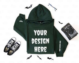 May include: A dark green hoodie with the text "YOUR DESIGN HERE" in white. The hoodie is paired with black Converse sneakers, a book titled "Black Cat Fortunes", and decorative bats. The sleeve reads "YOUR DESIGN HERE".