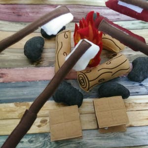 May include: A felt play set for a campfire with graham crackers, marshmallows, and sticks to roast them over a felt fire.