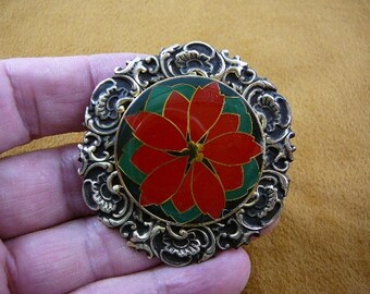 Könnte beinhalten: Eine runde, goldfarbene Brosche mit einem verzierten, gerollten Rahmen. In der Mitte befindet sich eine rote Weihnachtsstern-Blume mit grünen und goldenen Akzenten.