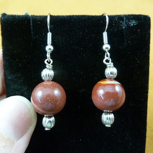 May include: A pair of silver dangle earrings with red and white agate stone beads.