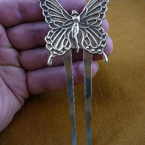 May include: A gold-tone butterfly hair comb with a detailed design. The butterfly has a delicate, feminine figure in the center. The comb has two long, thin tines.