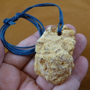 May include: A yellow amber pendant with a rough, textured surface. The pendant is attached to a blue cord.