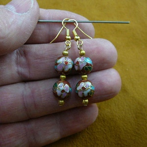 May include: A pair of gold dangle earrings with two red, white, and green enamel beads on each earring. The beads are decorated with floral patterns.