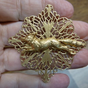 May include: A gold-toned brooch featuring a detailed fox design set within a delicate, intricate filigree pattern.