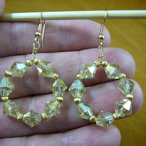 May include: A pair of gold tone earrings with a circle of clear faceted glass beads.
