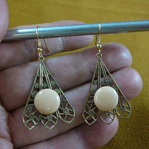 May include: A pair of gold tone earrings with a delicate filigree design and a round, off-white cabochon stone in the center of each earring.
