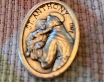 May include: Silver oval pendant necklace featuring a depiction of Saint Anthony holding a baby. The pendant has the words "St. Anthony" inscribed on the top and "Italy" inscribed on the bottom.