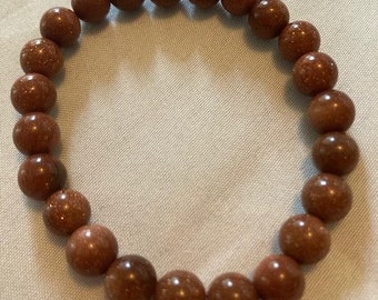 May include: A brown beaded bracelet made of round, speckled stones.