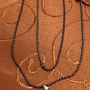 Puede incluir: Un collar de cadena de plata con un colgante de &aacute;ngel morado y azul. El &aacute;ngel est&aacute; hecho de una piedra con un patr&oacute;n de remolino.
