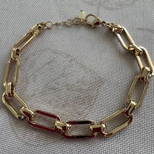 Bracciale color oro chiamato Paper Clip, proveniente da una vendita di beni di prima necessità, confezione originale, catena di estensione, mai indossato, marca Avon.