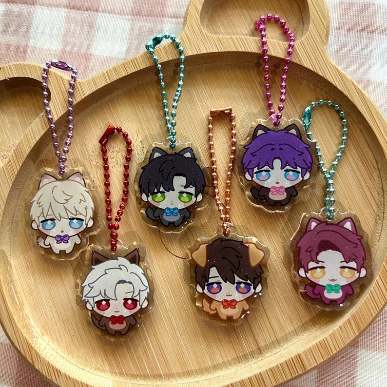 Pu&ograve; includere: Sei portachiavi in acrilico raffiguranti personaggi in stile chibi con orecchie da animale, ognuno attaccato a una catenella a palline in metallo colorato. I personaggi hanno colori di capelli, occhi e papillon distinti.