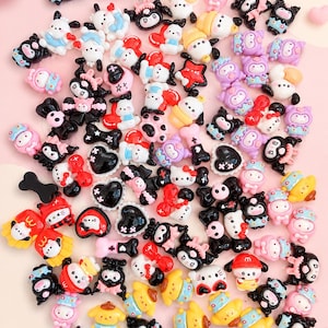 May include: A collection of small, colorful resin cabochons featuring various cartoon characters, hearts, bows, and bone shapes in shades of pink, black, white, yellow, and blue, designed for crafting and decorative embellishments.