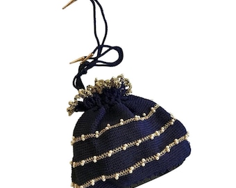 May include: Navy blue drawstring bag with gold-colored accents and pearl-like beads. The bag features a drawstring closure with gold-colored tips. The top edge is trimmed with gold-colored lace.
