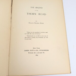 Pu&ograve; includere: Libro aperto con il titolo "The Legend of the Thorn Road" di Evelyn Nichols Kerr. Pubblicato a New York da James Pott & Co., Publishers nel 1897. Contiene una citazione biblica.