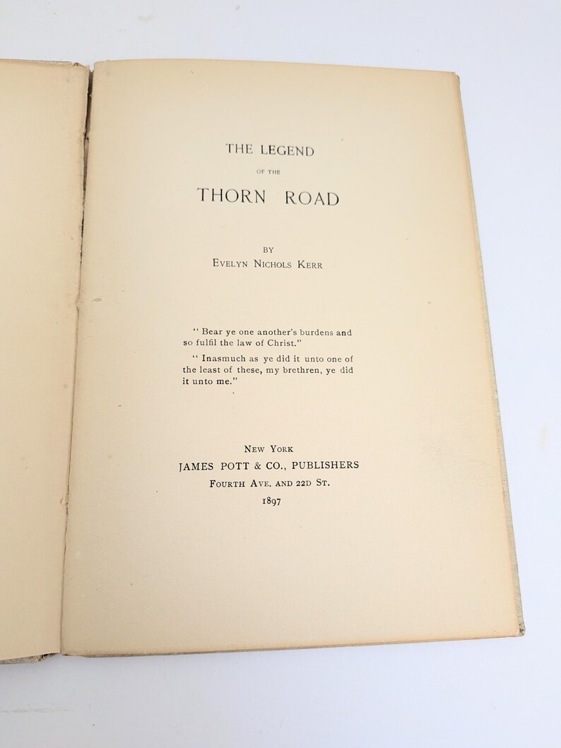 Pu&ograve; includere: Libro aperto con il titolo "The Legend of the Thorn Road" di Evelyn Nichols Kerr. Pubblicato a New York da James Pott & Co., Publishers nel 1897. Contiene una citazione biblica.
