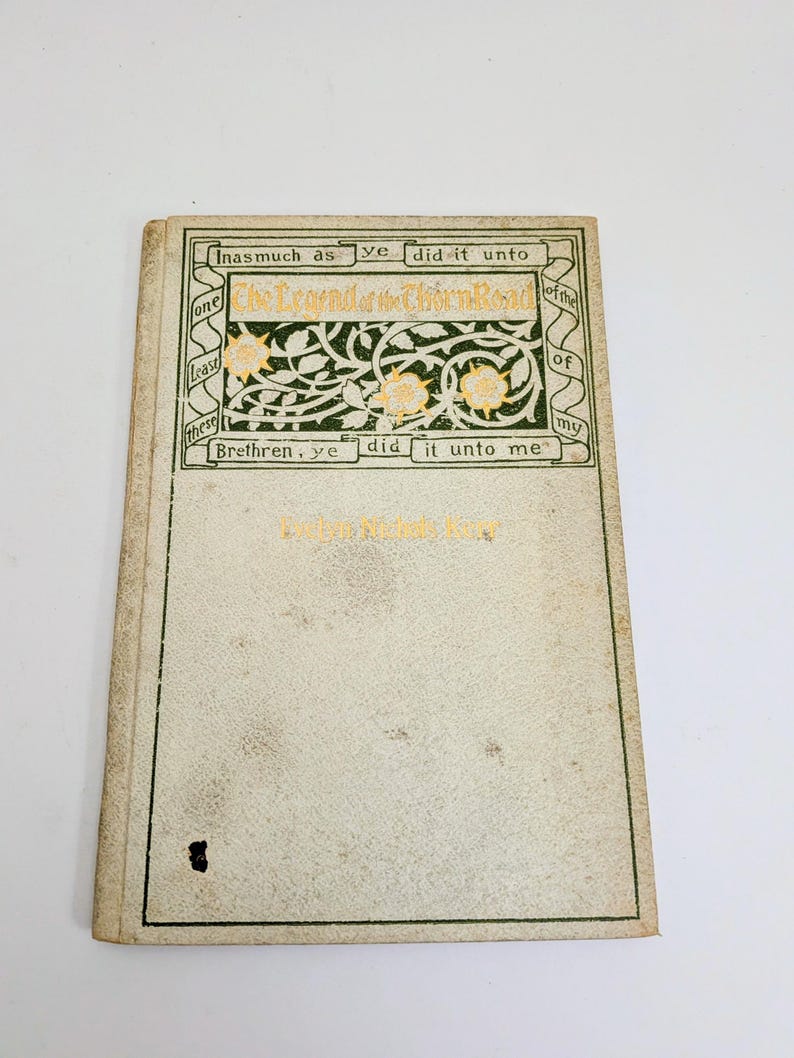 Pu&ograve; includere: Libro d'epoca intitolato "The Legend of the Thorn Road" con scritte dorate e bordo decorativo verde e oro. La copertina &egrave; bianco sporco con macchie. Il titolo e una citazione religiosa sono visibili.