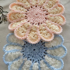 Puede incluir: Dos posavasos de ganchillo hechos a mano con diseño de flor de margarita. Un posavasos es rosa y crema, el otro es blanco y azul. Los posavasos están hechos de hilo suave y son perfectos para proteger las superficies de bebidas frías o calientes.