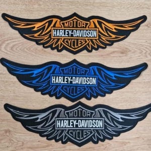Pode incluir: Três patches de motocicleta Harley-Davidson com asas pretas e um logotipo branco. Os patches são laranja, azul e cinza.