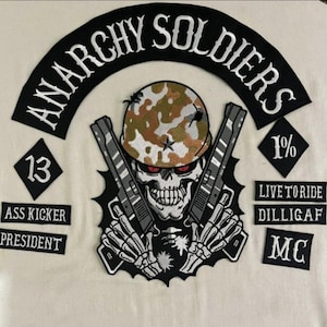 Op de afbeelding: Zwart-witte geborduurde patch met een schedel die een camouflagehelm draagt en twee pistolen vasthoudt. De patch zegt "Anarchy Soldiers" in een zwarte boog boven de schedel en "1%" in een zwarte ruit rechts van de schedel. Onder de schedel bevinden zich vier zwarte ruitvormige patches met de tekst "13", "Ass Kicker", "President" en "Live to Ride Dilligaf MC".