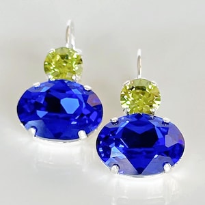 May include: A pair of silver dangle earrings with a large oval blue crystal and a smaller round green crystal on top.