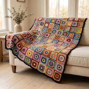 May include: A handmade crochet blanket featuring a vibrant granny square pattern in a multitude of colors including red, blue, yellow, green, and purple. The blanket is finished with a solid black border that frames the colorful square motifs.