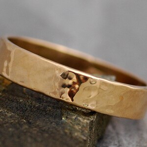 May include: A hammered gold wedding band with a matte finish.