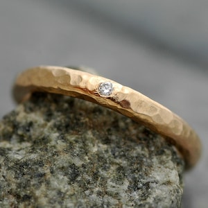 May include: A hammered gold band with a single small diamond set in the center.