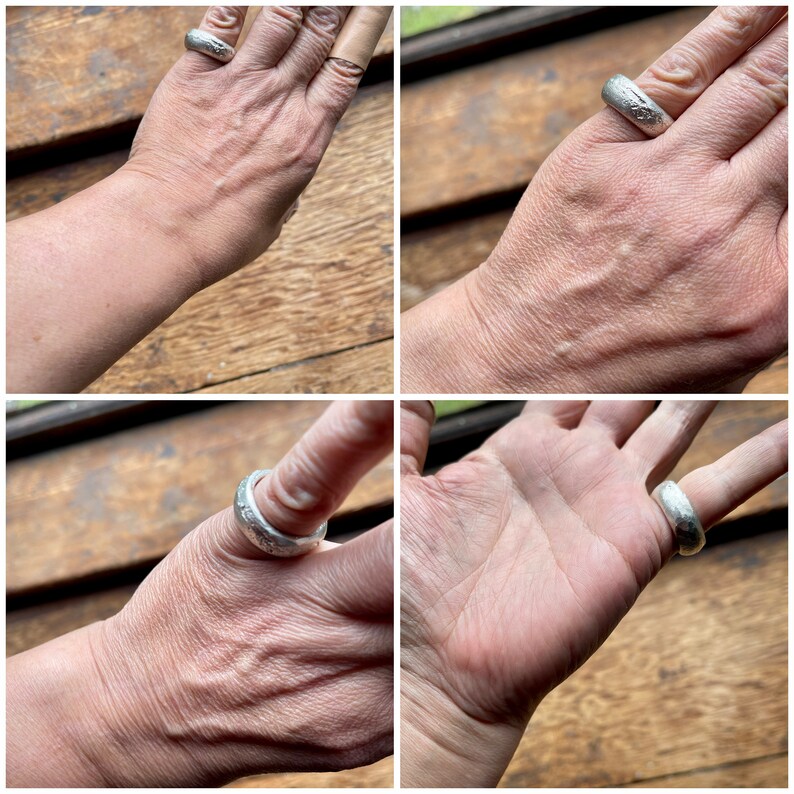 May include: A silver ring with a textured surface. The ring is worn on a person's finger.