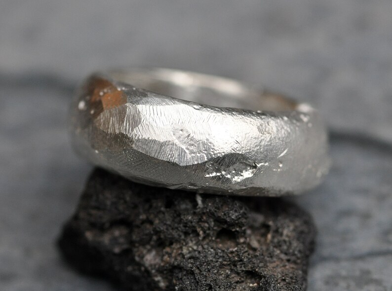 May include: A silver ring with a hammered, textured finish. The ring is thick and has a rounded shape.