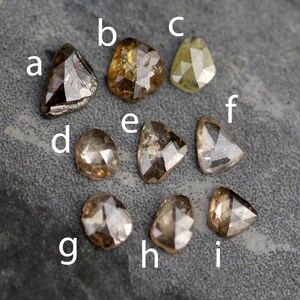 May include: Nine rough cut diamonds in various shapes and sizes. The diamonds are brown, grey, and yellow in colour.