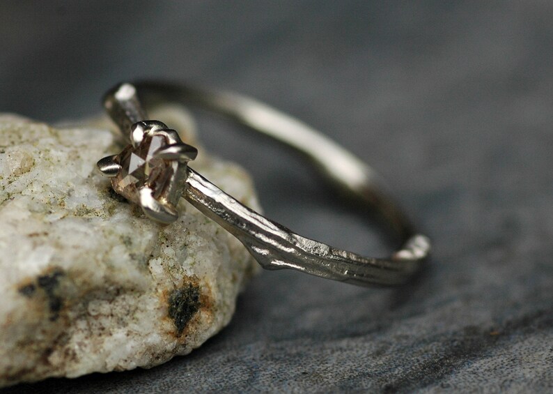 May include: A silver ring with a rough, textured band and a single, clear, faceted gemstone.