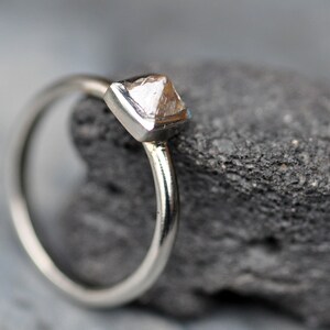 May include: A silver ring with a clear, faceted, pyramid-shaped gemstone.