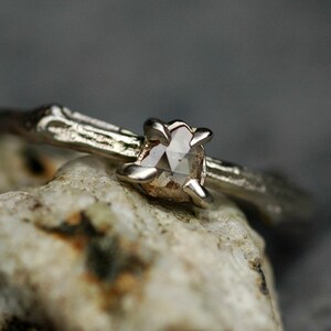 May include: A silver ring with a rough, natural-looking band and a clear, faceted gemstone set in the centre.
