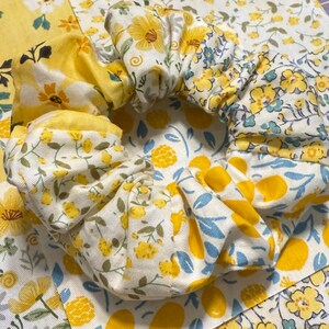May include: A white and yellow floral fabric scrunchie with a blue and white floral pattern on the inside.