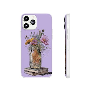 May include: A lavender phone case with a floral design. A mason jar filled with colorful flowers sits on a stack of books. The flowers include pink cosmos, yellow blooms, and blue wildflowers. The case has a white border and a camera cutout.