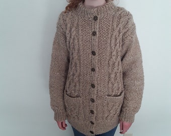 May include: A brown cable knit cardigan with a button front and two patch pockets. The cardigan is made of a soft, textured yarn.