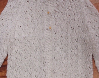 May include: White crocheted cardigan with a button-up front and a delicate lace pattern.