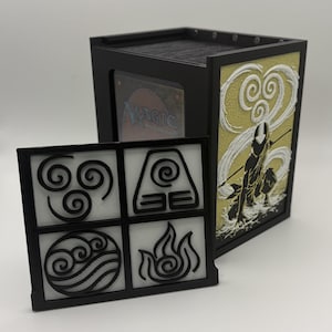 May include: Black and gold card storage box with a removable front panel featuring elemental symbols. The side panel displays a silhouette of a figure with a staff. The box contains a Magic: The Gathering card.