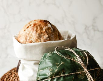 May include: A loaf of bread in a white cloth bag, wrapped in green and gold patterned food wrap with twine. The wrap has the text "Everyday Jade" printed on it.