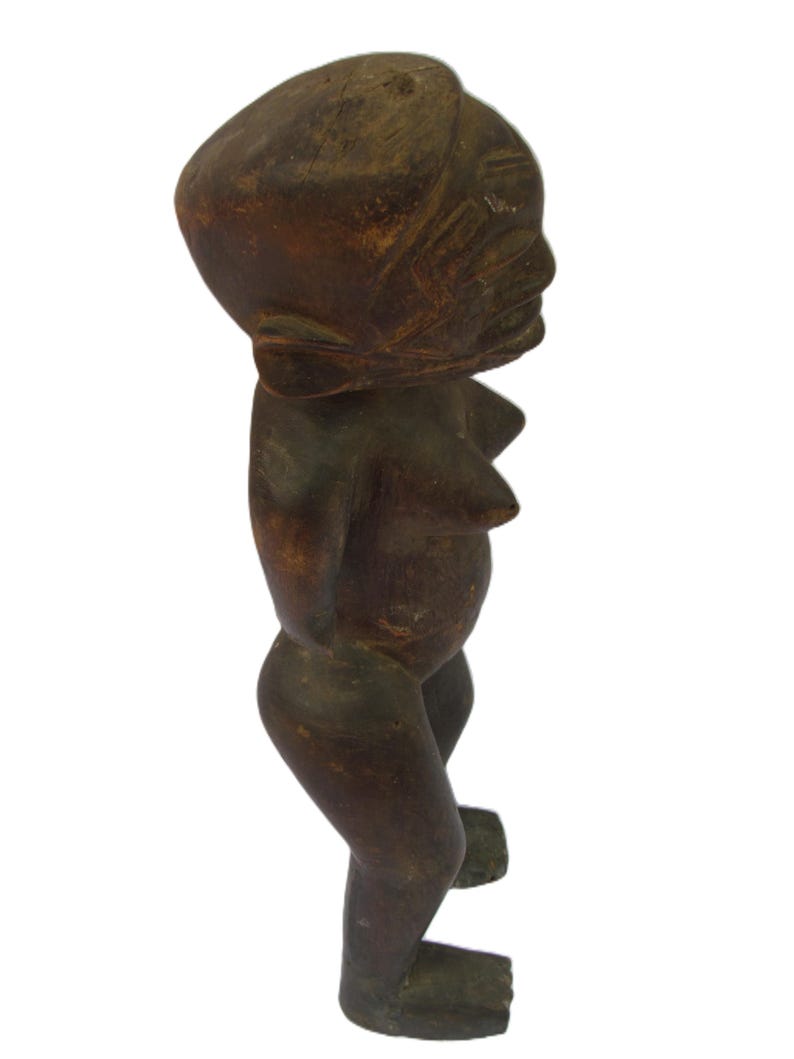 以下が含まれることがあります： 暗い茶色の木彫りの人物像。丸い頭と様式化された体を持つ。木目は見え、アンティークまたはヴィンテージの起源を示唆している。顔の特徴はシンプルに彫刻されている。