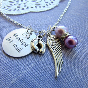 May include: Silver necklace with a charm that reads "Too beautiful for earth" and features a pair of baby footprints, an angel wing, and two purple beads.