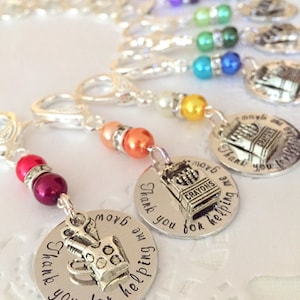 May include: A set of silver charm keychains with colorful beads. Each charm features a silver school supply image and the text "Thank you for helping me grow".