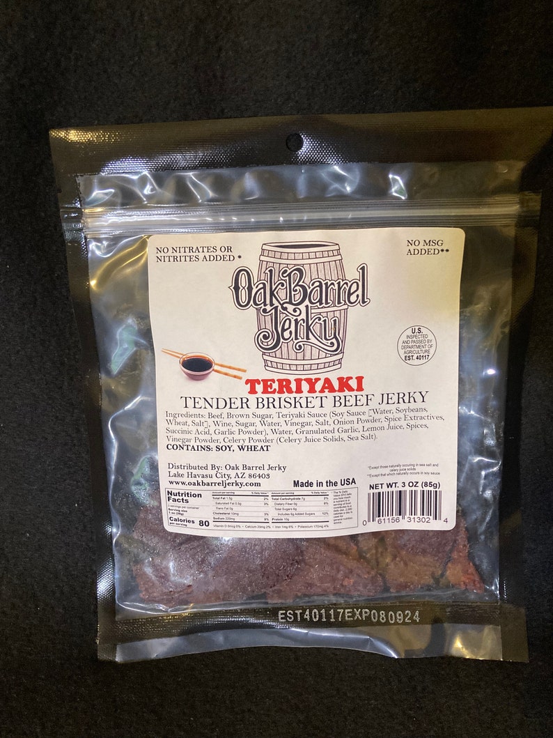 May include: A bag of Oak Barrel Teriyaki Tender Brisket Beef Jerky. The bag is white with a brown and white illustration of a barrel. The bag has a nutrition facts label and a net weight of 3 ounces (85 grams).