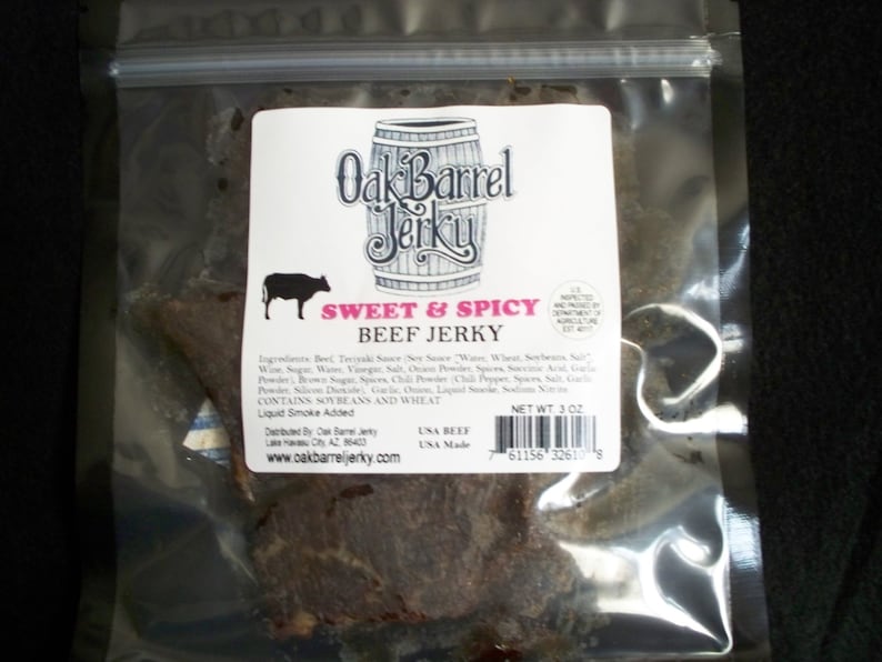 May include: A clear plastic bag containing a 3 oz bag of Oak Barrel Jerky, Sweet & Spicy Beef Jerky. The bag is sealed and has a label with the company's logo and product information.