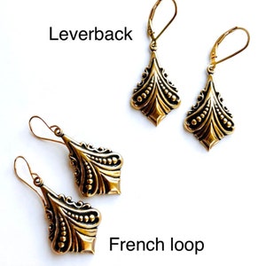 May include: Two pairs of gold-colored earrings. One pair features leverback closures, and the other has French loop closures. Both styles have a decorative, ornate design with a diamond-like shape and a series of small, raised dots.