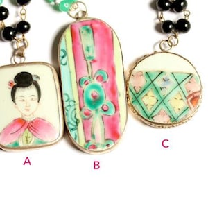 Puede incluir: Tres collares con colgantes vintage de porcelana pintados a mano. Los colgantes presentan diseños de inspiración asiática, incluyendo un retrato, motivos florales y formas geométricas. Los collares tienen cadenas de cuentas verdes y negras.