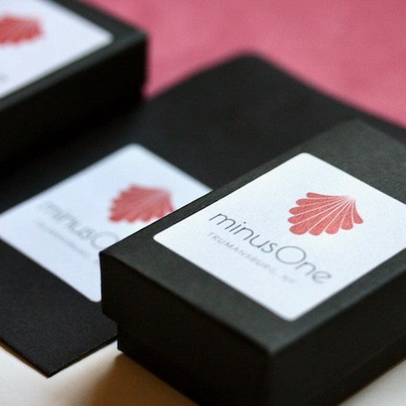 May include: Black box with a white label that says "minusOne TRUMANSBURG, NY" and a red seashell logo.