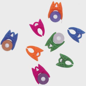 May include: A collection of colorful thread spool holders in various shades, including blue, orange, green, and pink. Each holder has a unique design and holds a small spool of thread. The spools are in shades of brown, purple, and white.