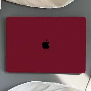 May include: A closed red laptop computer with an Apple logo on the lid.